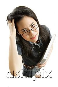 AsiaPix - Young woman with glasses, carrying book, scratching hair
