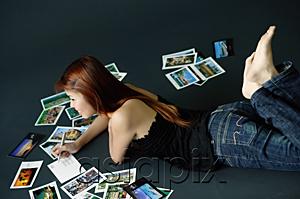 AsiaPix - Woman lying on floor, writing on backs of postcards