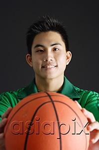 AsiaPix - Young man holding basketball, looking at camera
