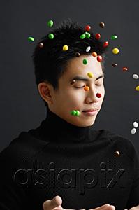 AsiaPix - Young man dressed in black, throwing multi coloured candy in the air