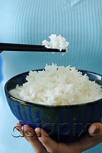 AsiaPix - Woman holding bowl of rice and chopstick, close up