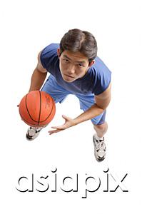 AsiaPix - Young man holding basketball, looking up at camera
