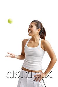 AsiaPix - Young woman tossing tennis ball, hand on hip