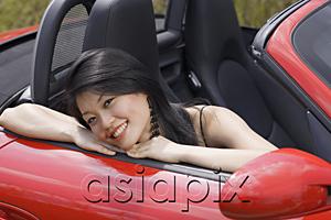 AsiaPix - Woman sitting in red sports car, smiling at camera