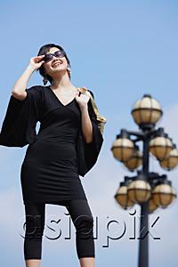AsiaPix - Woman dressed in black, carrying bag over shoulder, adjusting sunglasses