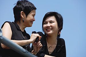 AsiaPix - Women side by side, smiling, looking away