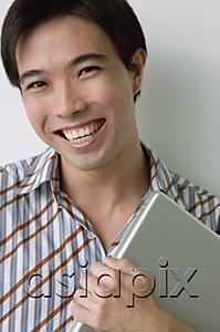 AsiaPix - Man smiling at camera, holding laptop