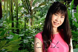 AsiaPix - Woman standing in garden, smiling at camera