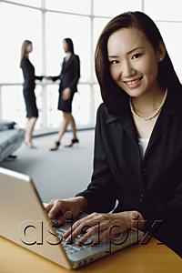 AsiaPix - Portrait of businesswoman using laptop, smiling at camera