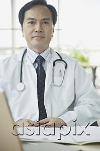AsiaPix - Doctor sitting at desk, looking at camera, serious expression