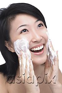 AsiaPix - Young woman putting facial cleanser on her face
