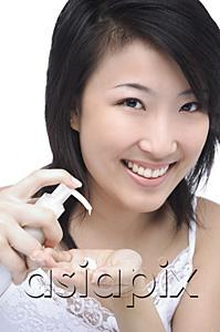 AsiaPix - Young woman putting moisturizer on hand