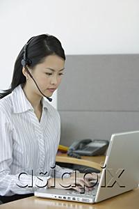 AsiaPix - Young woman using laptop, wearing hands free device