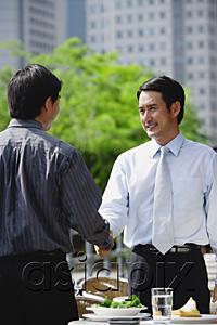 AsiaPix - Two businessman at outdoor cafe, shaking hands