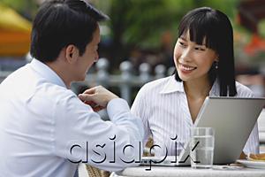 AsiaPix - Businesswoman and businessman at outdoor cafe, with laptop