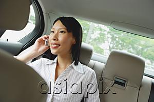 AsiaPix - Businesswoman in backseat of car using mobile phone