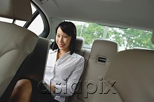 AsiaPix - Businesswoman in backseat of car using laptop, smiling