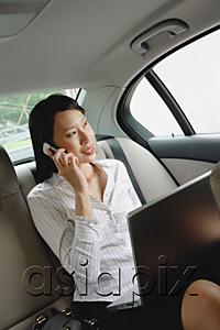 AsiaPix - Businesswoman in car using laptop and mobile phone