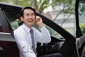 AsiaPix - Businessman sitting in car, using mobile phone, smiling