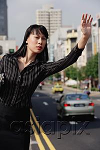 AsiaPix - Businesswoman hailing a taxi, frowning