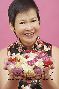 AsiaPix - Mature woman holding bowl of flowers, smiling