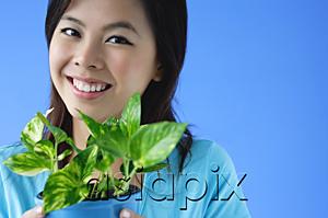AsiaPix - Young woman holding plant pot, portrait