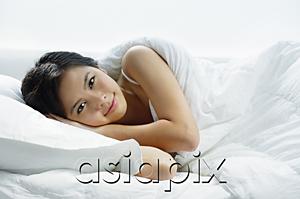 AsiaPix - Young woman lying on bed, looking at camera