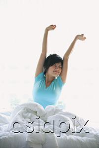 AsiaPix - Woman stretching in bed, arms raised