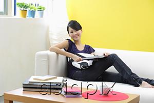 AsiaPix - Woman sitting on sofa, looking at camera