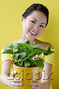 AsiaPix - Woman holding house plant, smiling