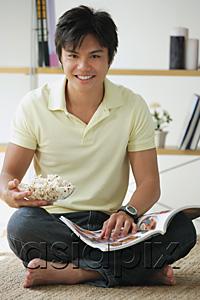AsiaPix - Man sitting on floor, with magazine and bowl of popcorn