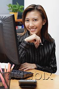 AsiaPix - Female executive at desk, hand on chin, smiling at camera