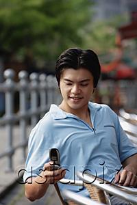 AsiaPix - Man sitting outdoors, using mobile phone, text messaging