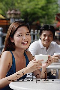 AsiaPix - Woman having coffee in cafe, man in the background