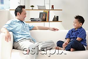 AsiaPix - Father and son sitting on sofa, smiling at each other