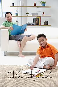 AsiaPix - Father sitting on sofa, son on floor with drawing pad