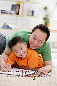 AsiaPix - Father and son at home, lying on floor with sketch pad, smiling at camera