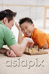 AsiaPix - Father and son lying on floor, playing chess, son laughing