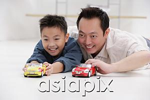 AsiaPix - Father and son lying on floor, playing with toy cars