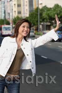 AsiaPix - Woman standing by road, flagging a cab