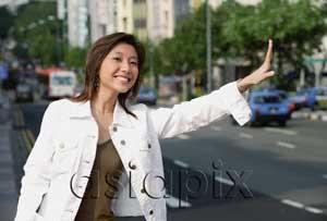 AsiaPix - Woman standing by road, waving for taxi