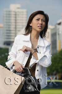 AsiaPix - Woman carrying bags, looking away, frowning
