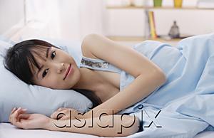 AsiaPix - Young woman lying on bed, smiling