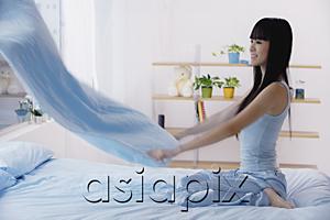 AsiaPix - Young woman holding blanket, making the bed