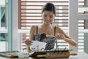 AsiaPix - Young woman in kitchen holding mixing bowl