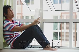 AsiaPix - Man sitting on bay window, reading a book