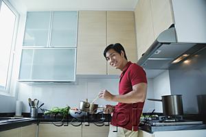 AsiaPix - Man cooking in kitchen, smiling at camera