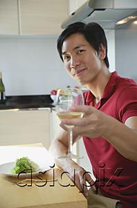 AsiaPix - Man sitting down for a meal, raising wine glass toward camera
