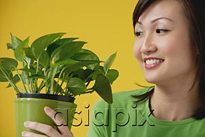AsiaPix - Young Woman looking at house plant