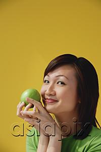 AsiaPix - Young Woman holding apple, smiling at camera